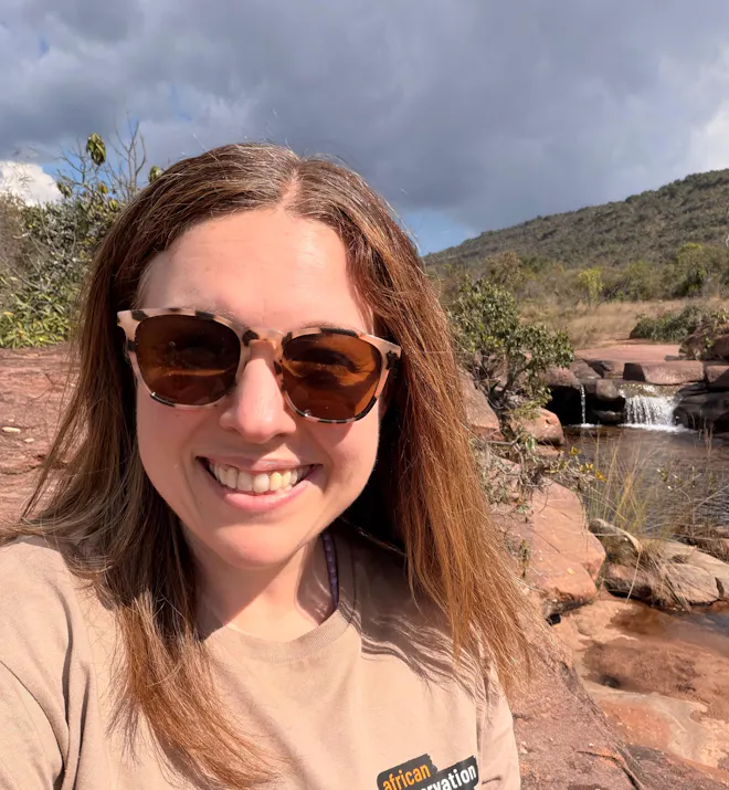Michelle Revai - Smiling in her ACE t-shirt in front of a waterfall