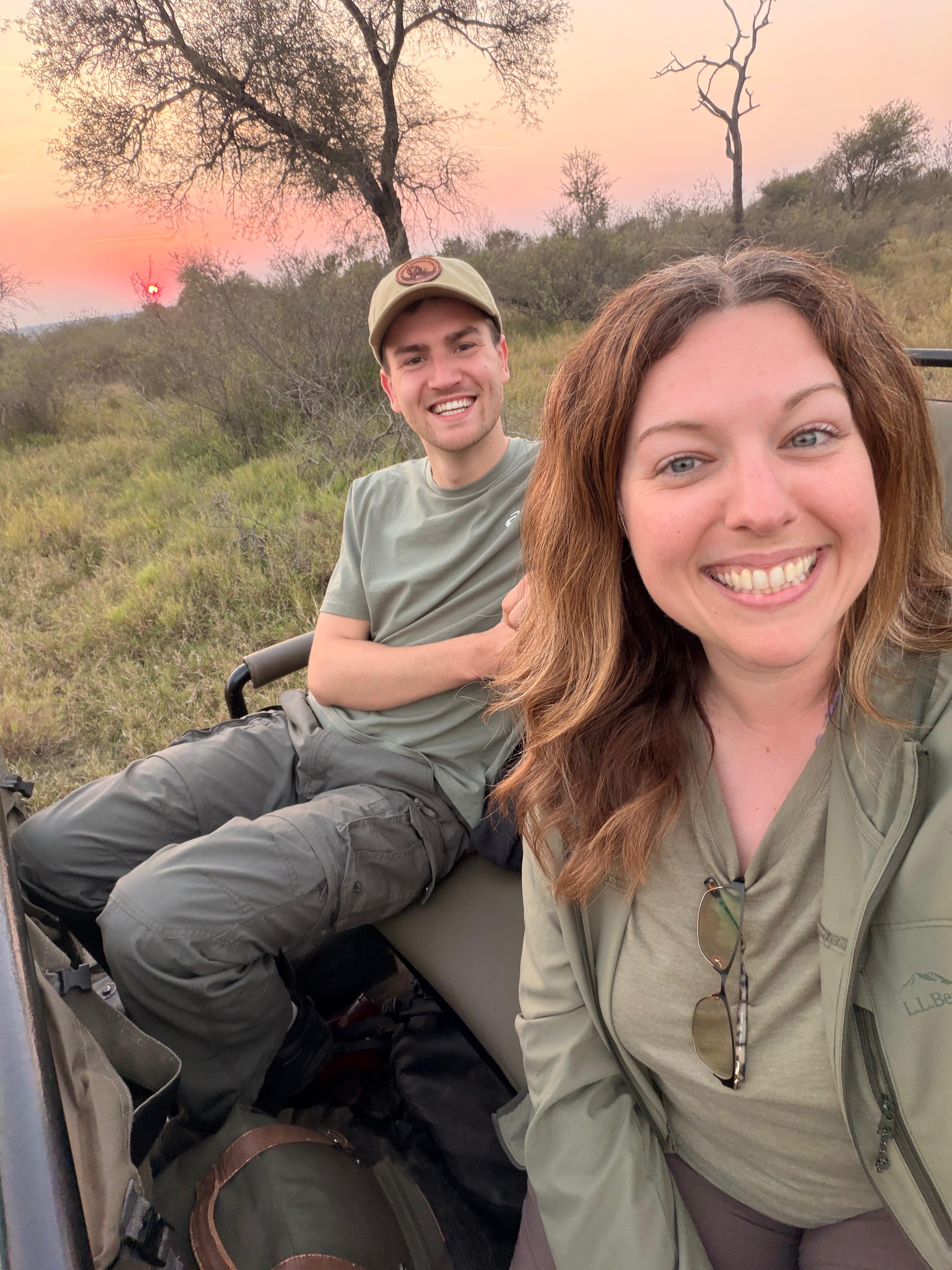 Michelle Revai - Smiling with fellow volunteer on vehicle in the bush at sunset on Vikela Kruger project