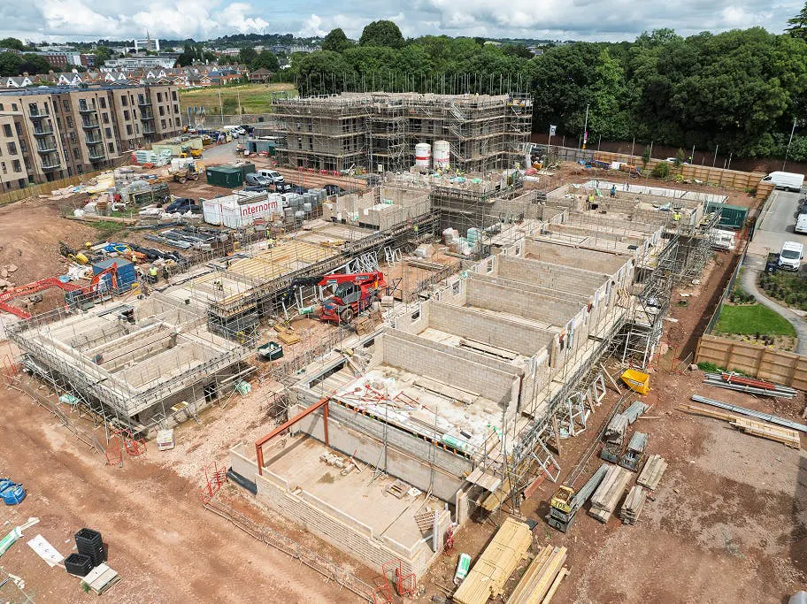 In Phase 2, walls are rising plot by plot, with scaffolding now in place to support the next lift.