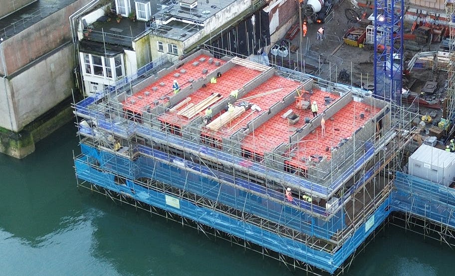 Formwork and reinforcement laid across the upper deck of the bank building, with the waterfront below and the new floor structure taking form above it.