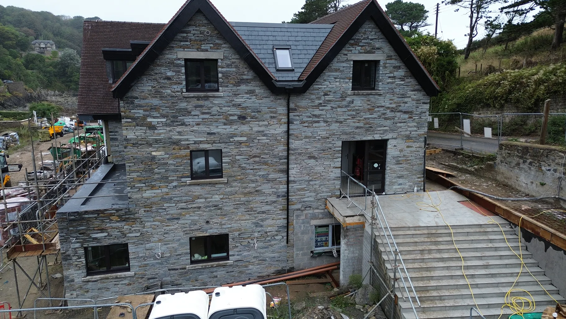 The houses at Lee Bay near external completion, with stonework and landscaping work continuing across the site.
