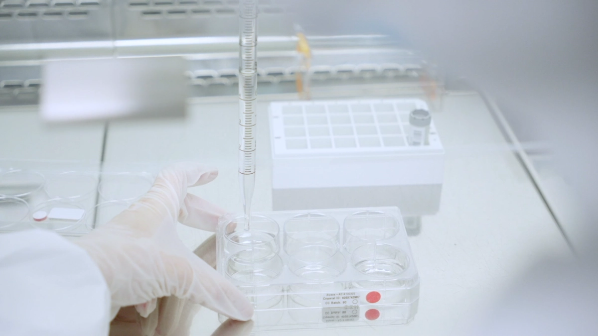A laboratory professional in a white lab coat is holding a test tube, indicating involvement in scientific research or analysis.
