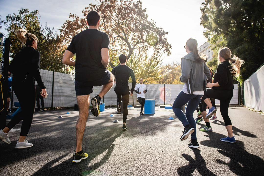 Several runners participating in a warmup exercise, surrounded by urban scenery.