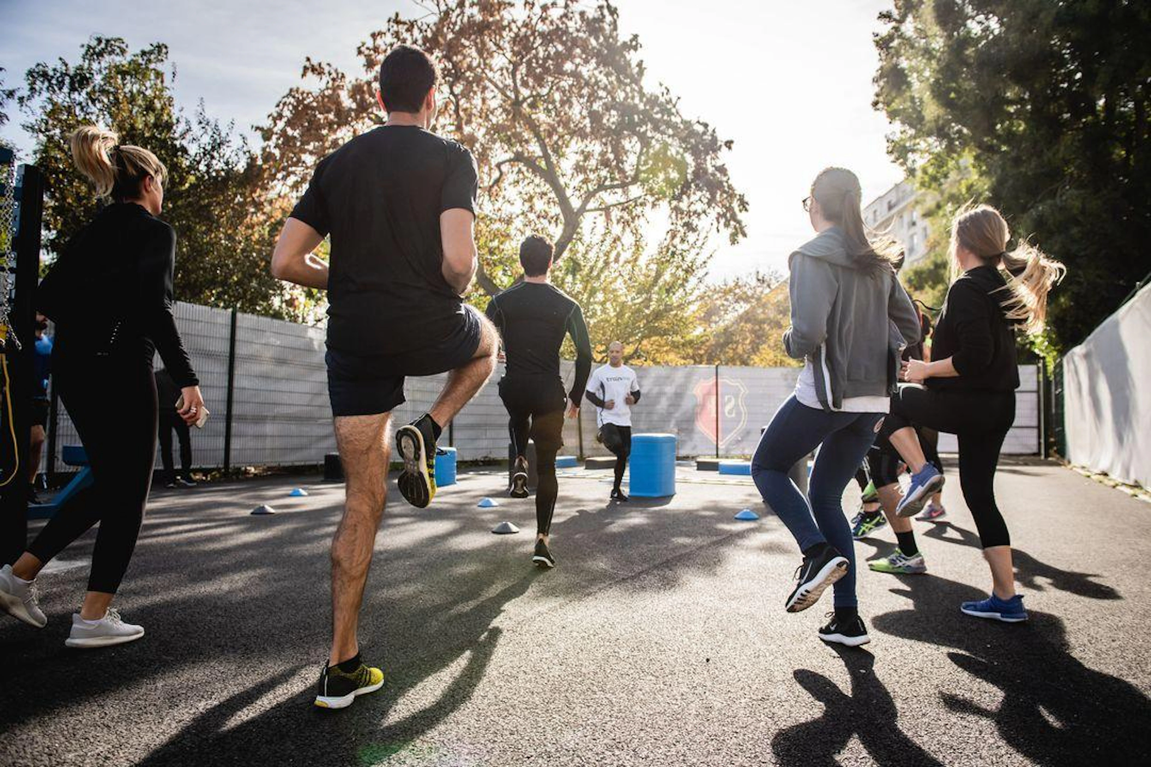Several runners participating in a warmup exercise, surrounded by urban scenery.