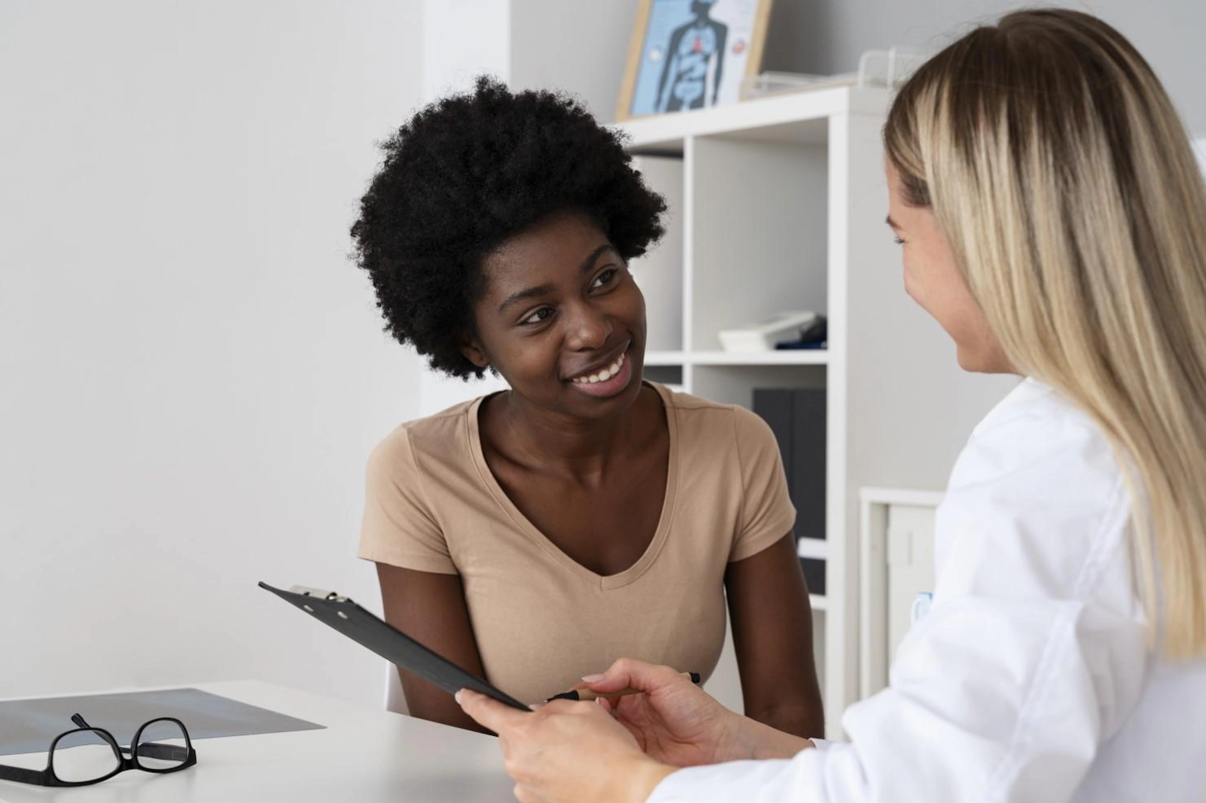 A doctor and a woman are seated at a desk, engaged in a discussion about the woman's health and treatment options.