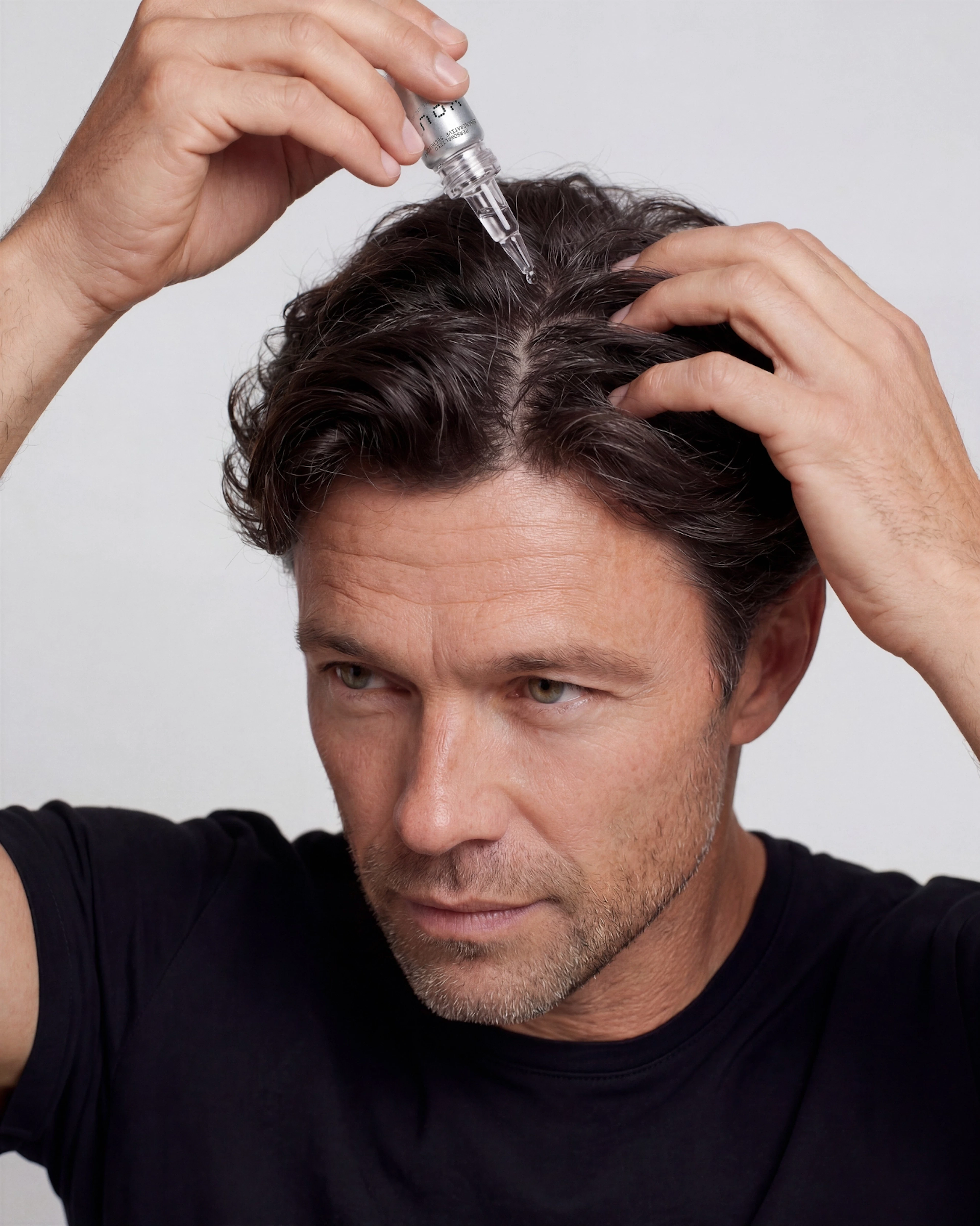 A man applies hair serum, focusing on achieving better hair growth.