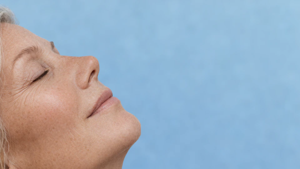 A woman with her eyes shut and head held high, reflecting a moment of serenity and self-reflection.