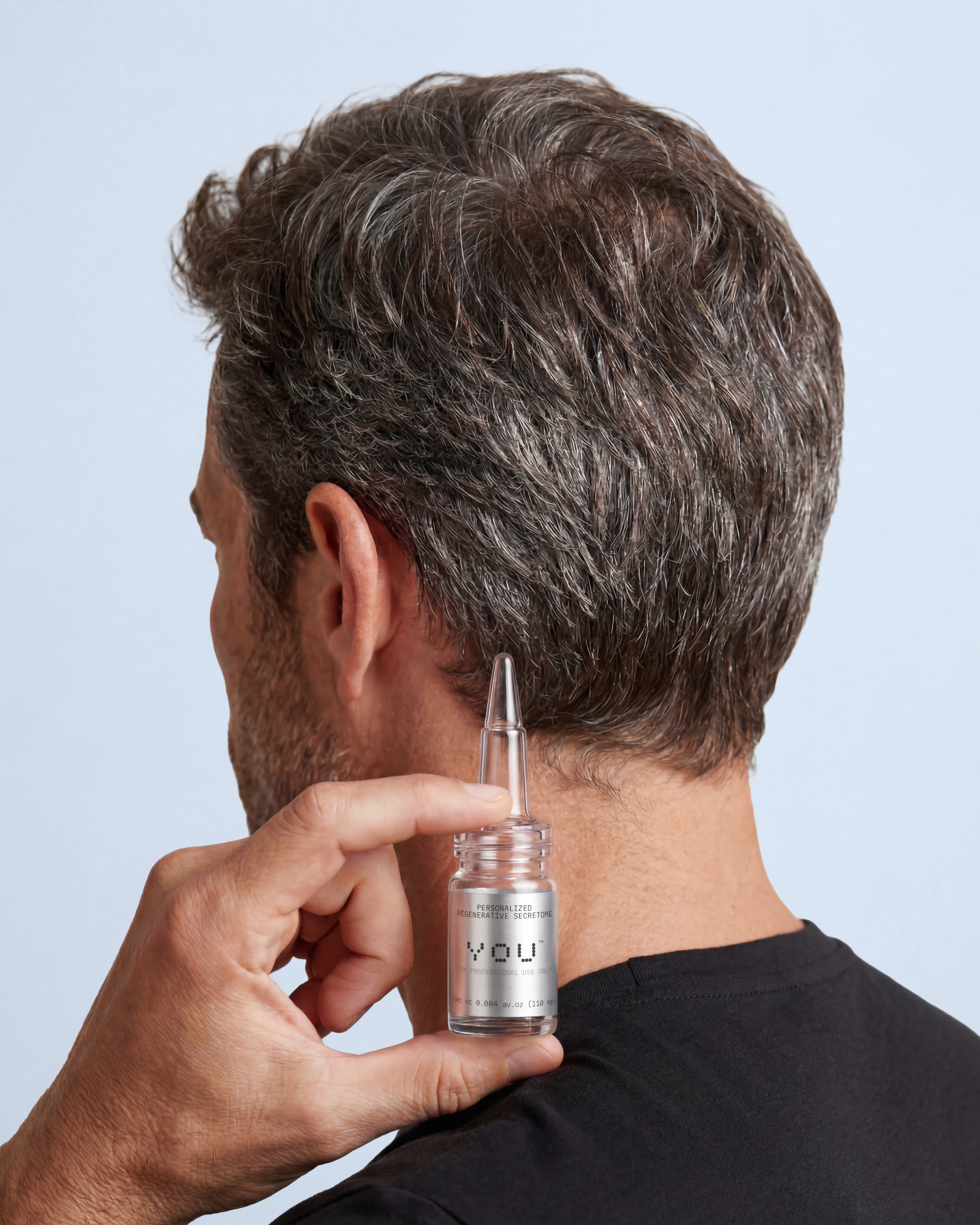 A man displays a secretome bottle, focusing on its label while holding it in his hand.