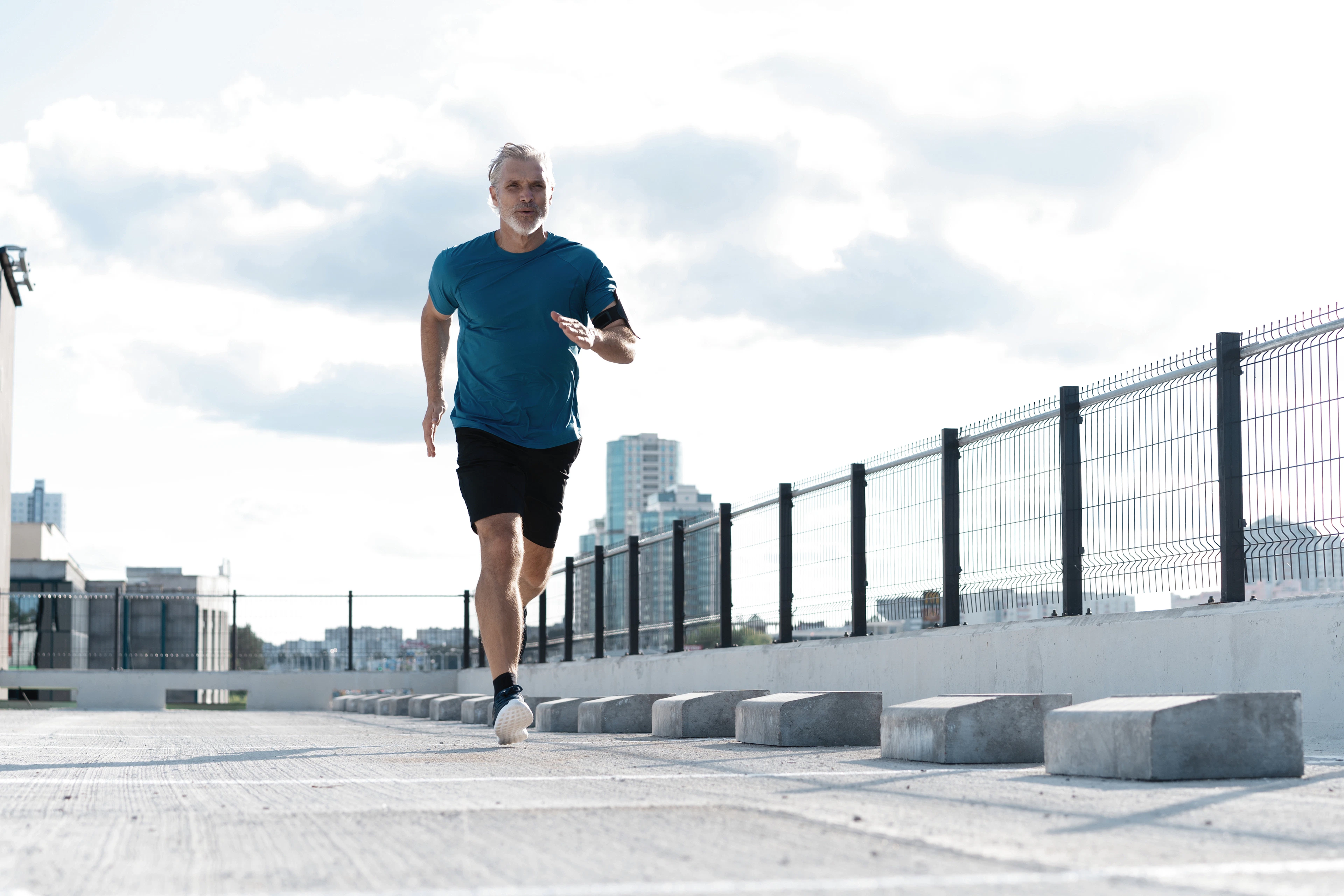 A man jogs on a concrete path, showcasing a determined expression and athletic attire.
