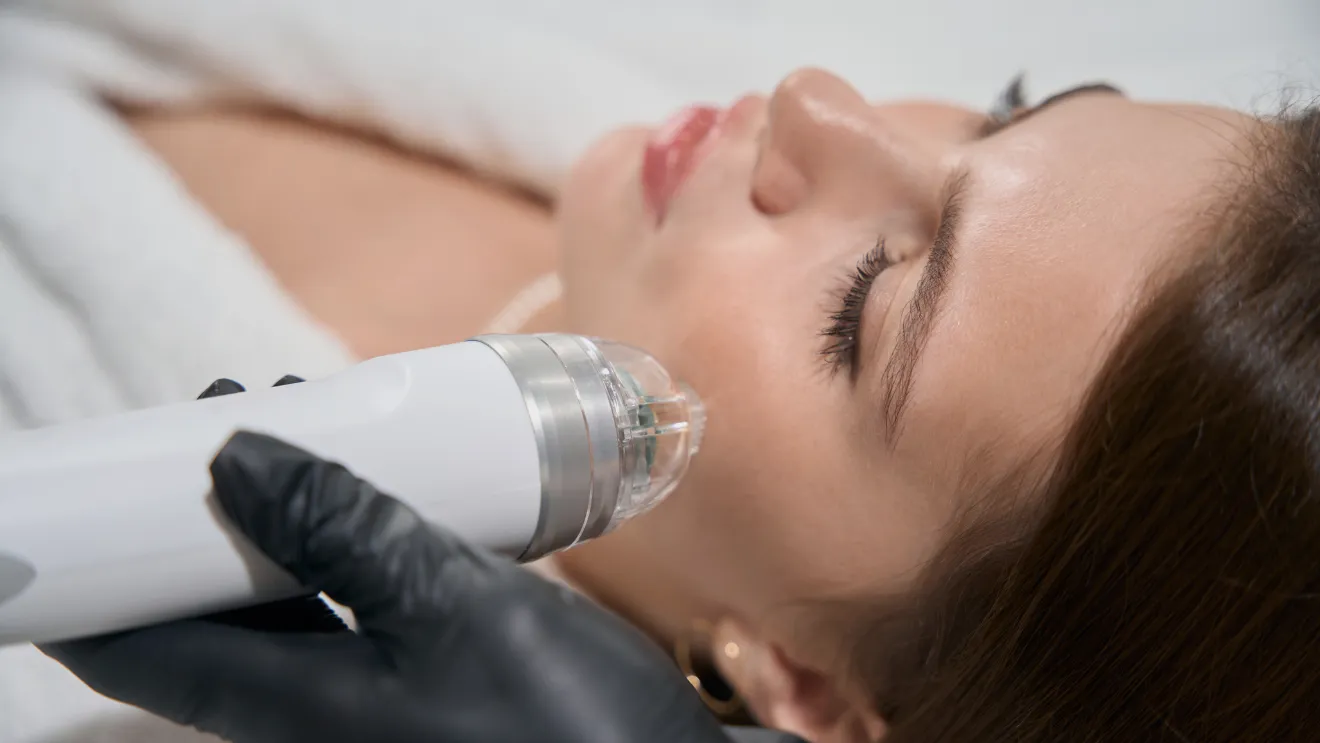 A woman receiving a facial treatment using an electric device, relaxing in a spa setting.