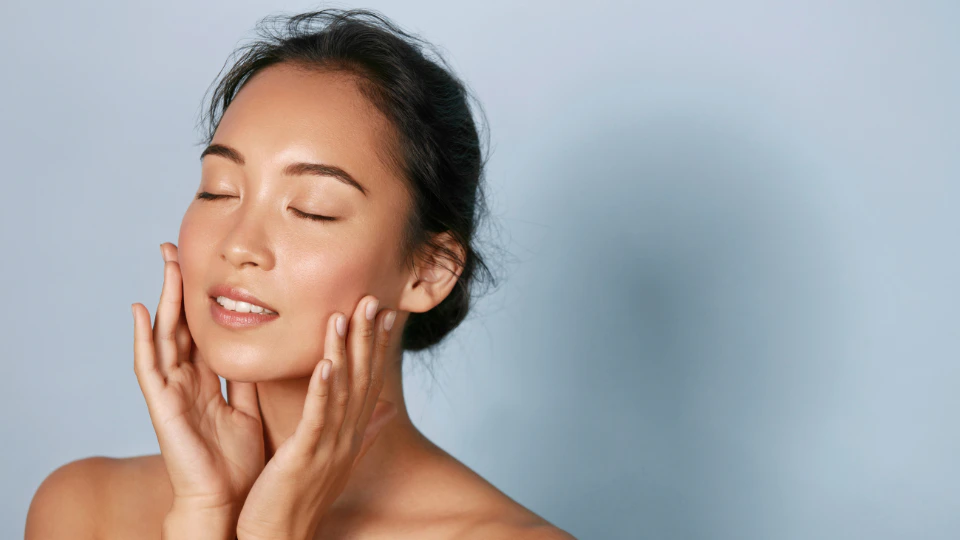 A woman is seen with her hands placed on her face, suggesting a moment of self-care or reflection.
