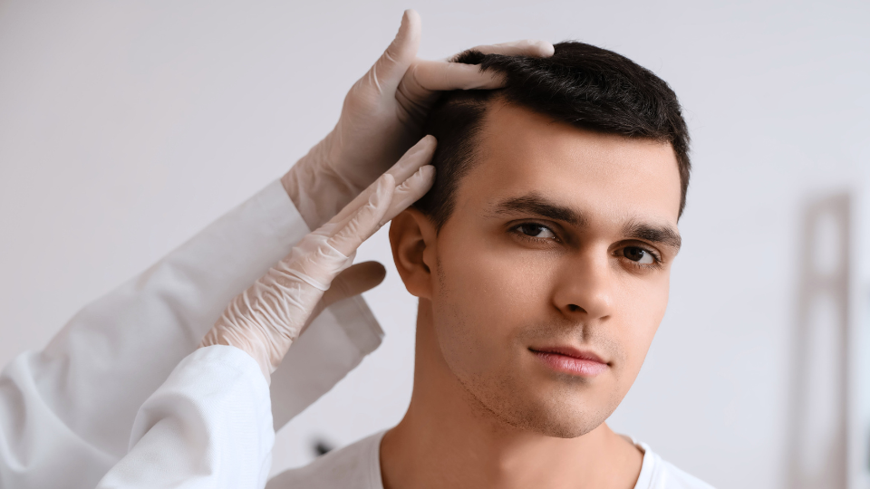 A doctor closely examining a man's hair.