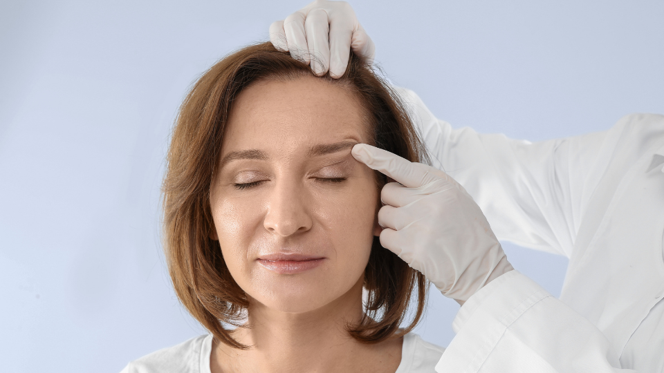 A woman receiving a facial examination from a doctor in a clinical setting.
