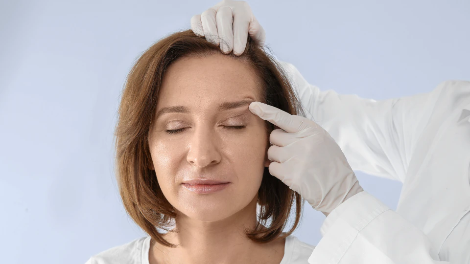A woman receiving a facial examination from a doctor in a clinical setting.