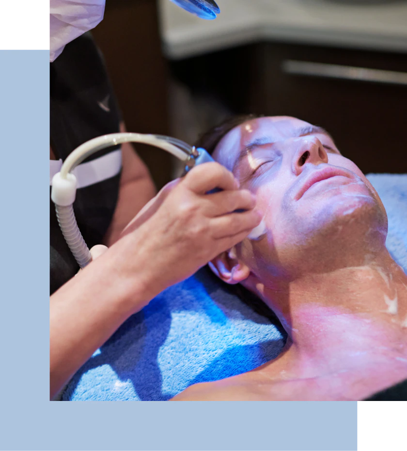 A man relaxes in a spa while receiving a facial treatment, surrounded by calming decor and soft lighting.