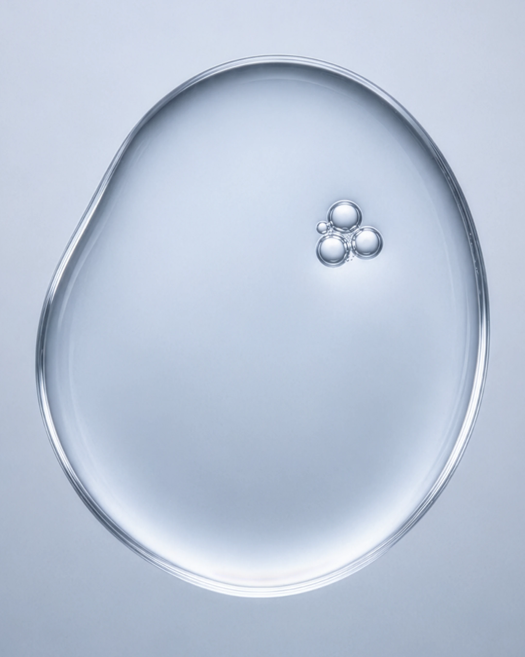 Close-up of serum drops on a clear blue backdrop, highlighting the reflective surfaces and vibrant hues.