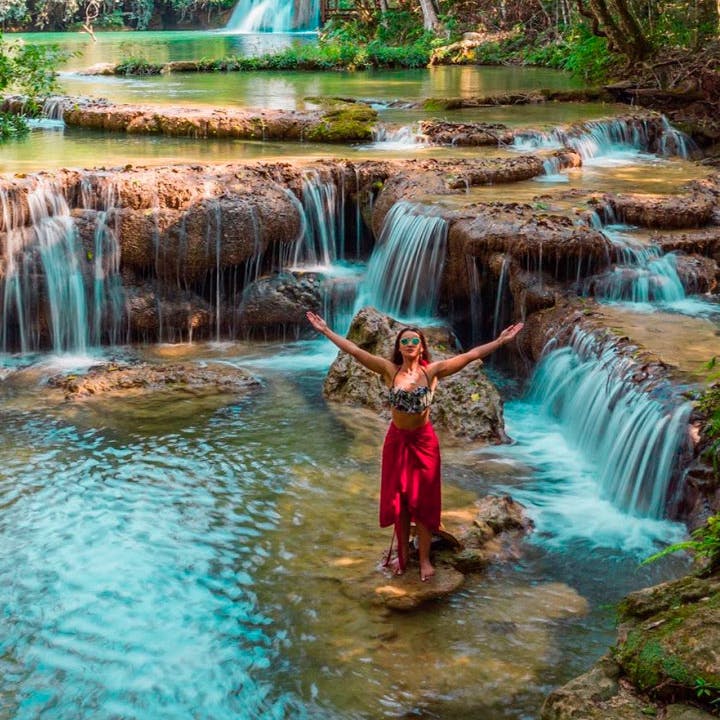 mulher de braços abertos em meio a cachoeira