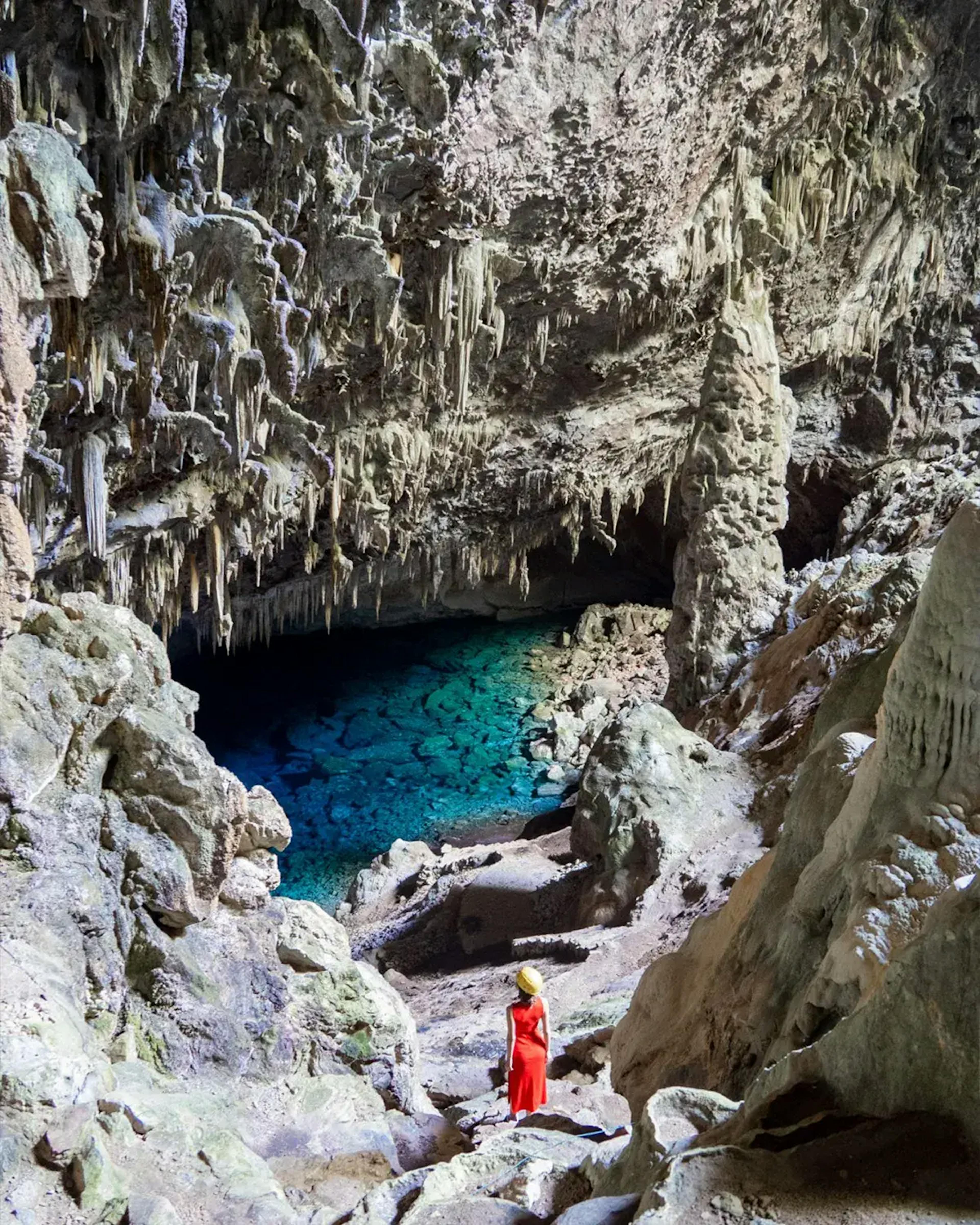 Turista percorrendo corredores rochosos dentro da Gruta do Lago Azul