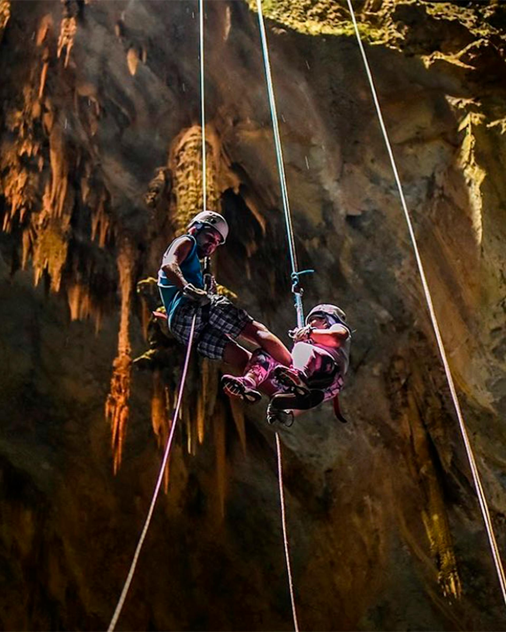 Turistas em descida de rapel elétrico e seguro para adentrar na caverna subterrânea que forma o Abismo Anhumas