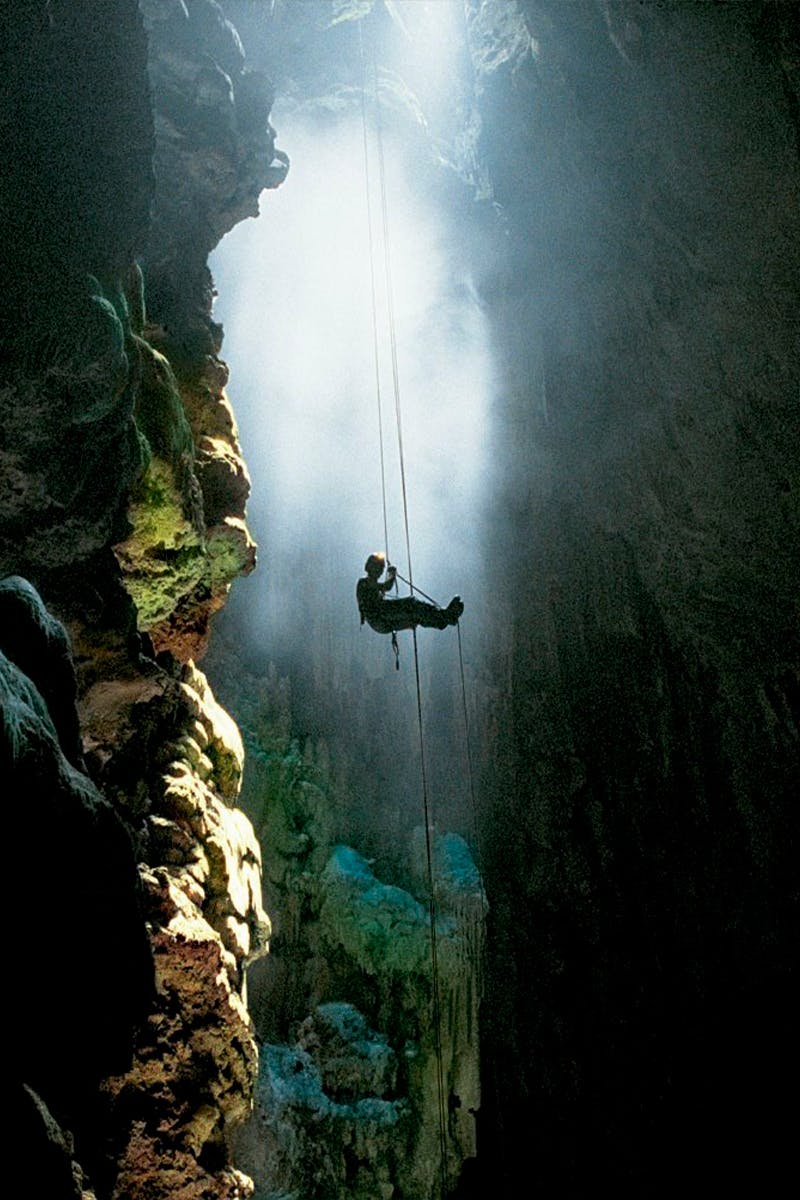 Turista fazendo a descida de rapel do alto da abertura do Abismo Anhumas