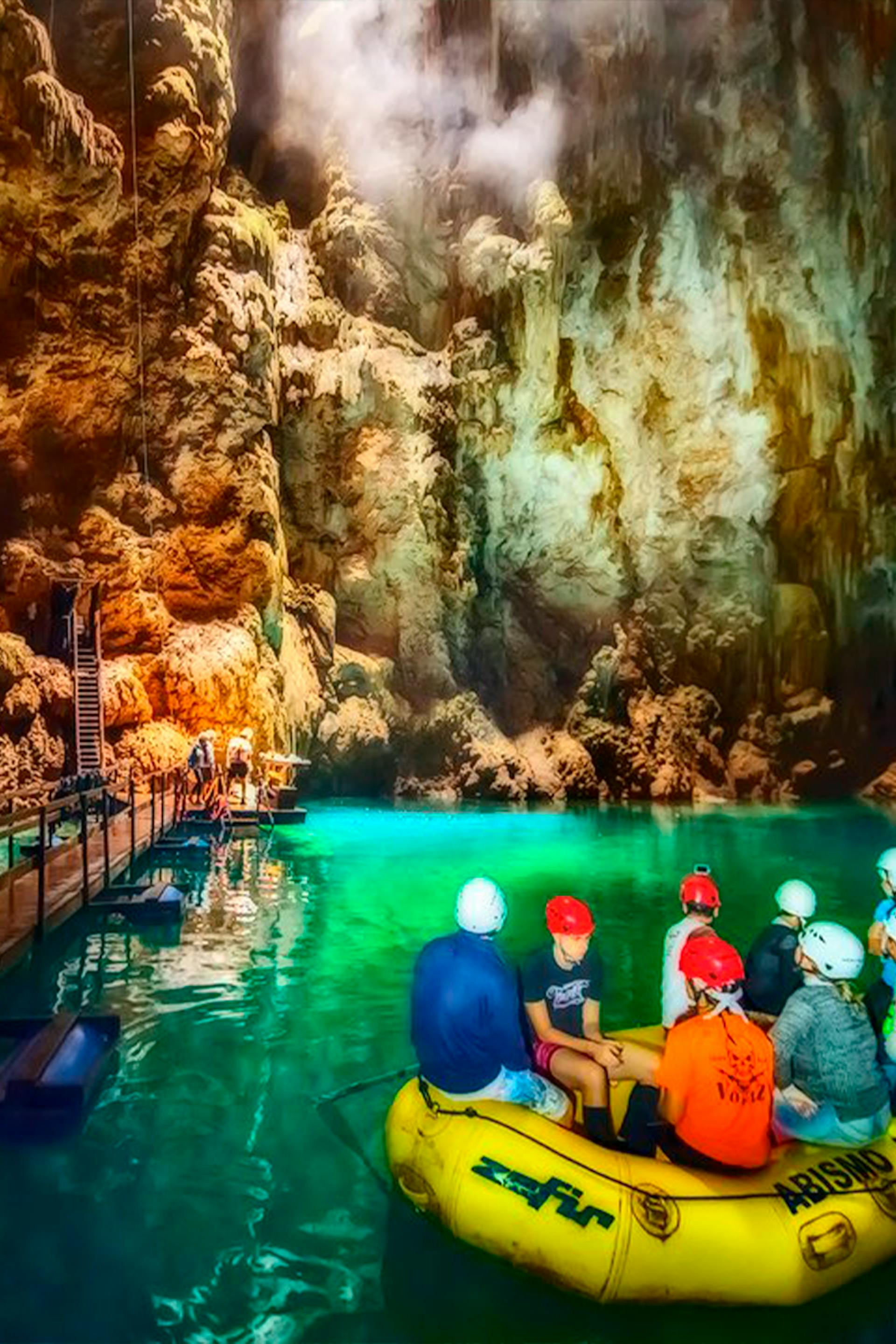 Turistas contemplando formações naturais em passeio de bote pelo lago subterrâneo do Abismo Anhumas