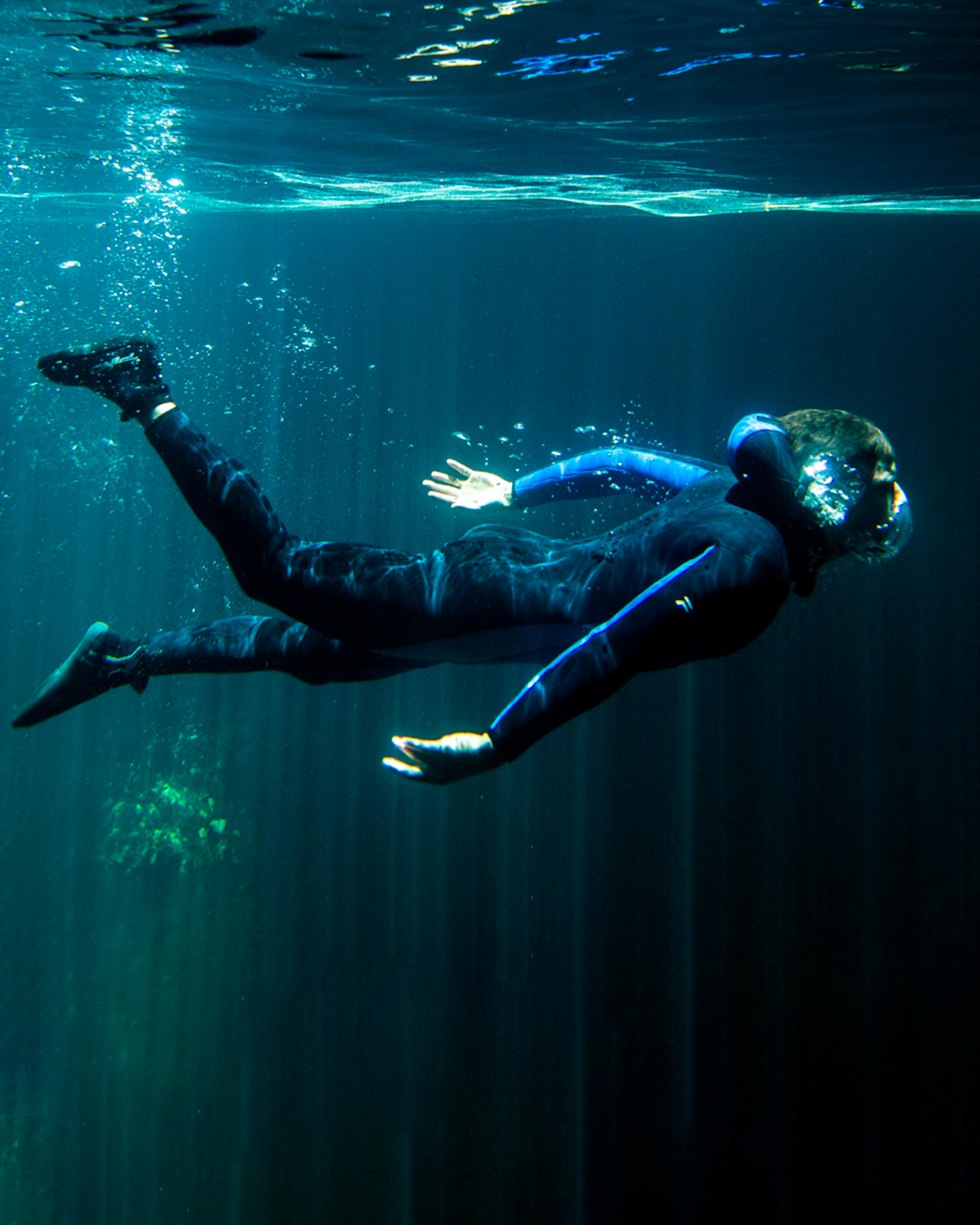 Turista submersa no lago do interior do Abismo Anhumas com visibilidade total, ilustrando a cristalinidade da água