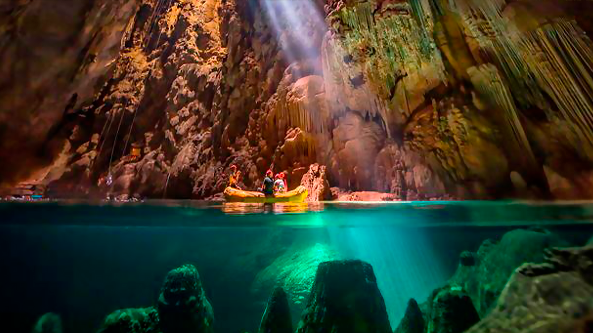 Iluminação natural entrando no interior da caverna do Abismo Anhumas sobre o bote inflável com turistas contemplando as formações naturais incríveis