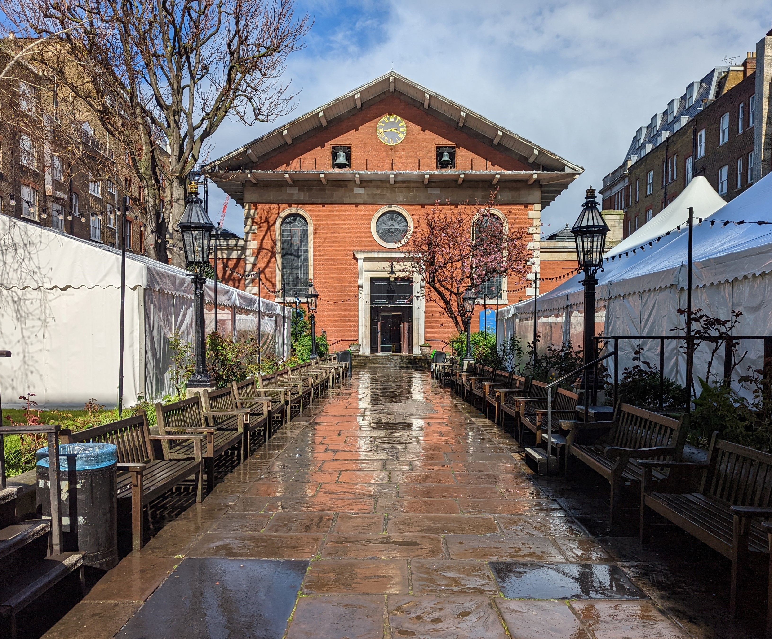 A view with the church entrance in the centre. On each side of the path there are large white marquees.