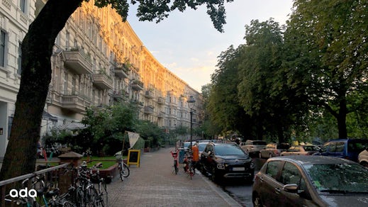 A row of apartment buildings to the left and a sidewalk and road to the right.