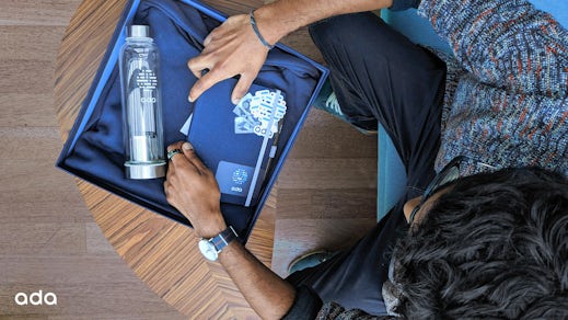 Photo shows Gobie unpacking a notepad, drink bottle, and stickers from his onboarding box.