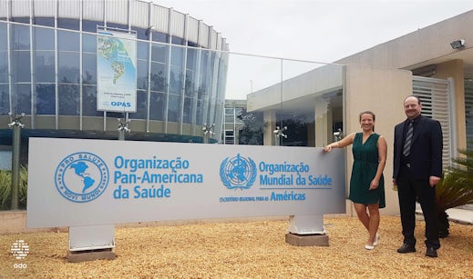 Henry and Martina are standing in front of the event sign.