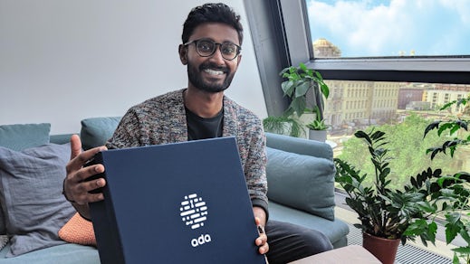 Gobie holding a navy blue employee box featuring Ada's logo.