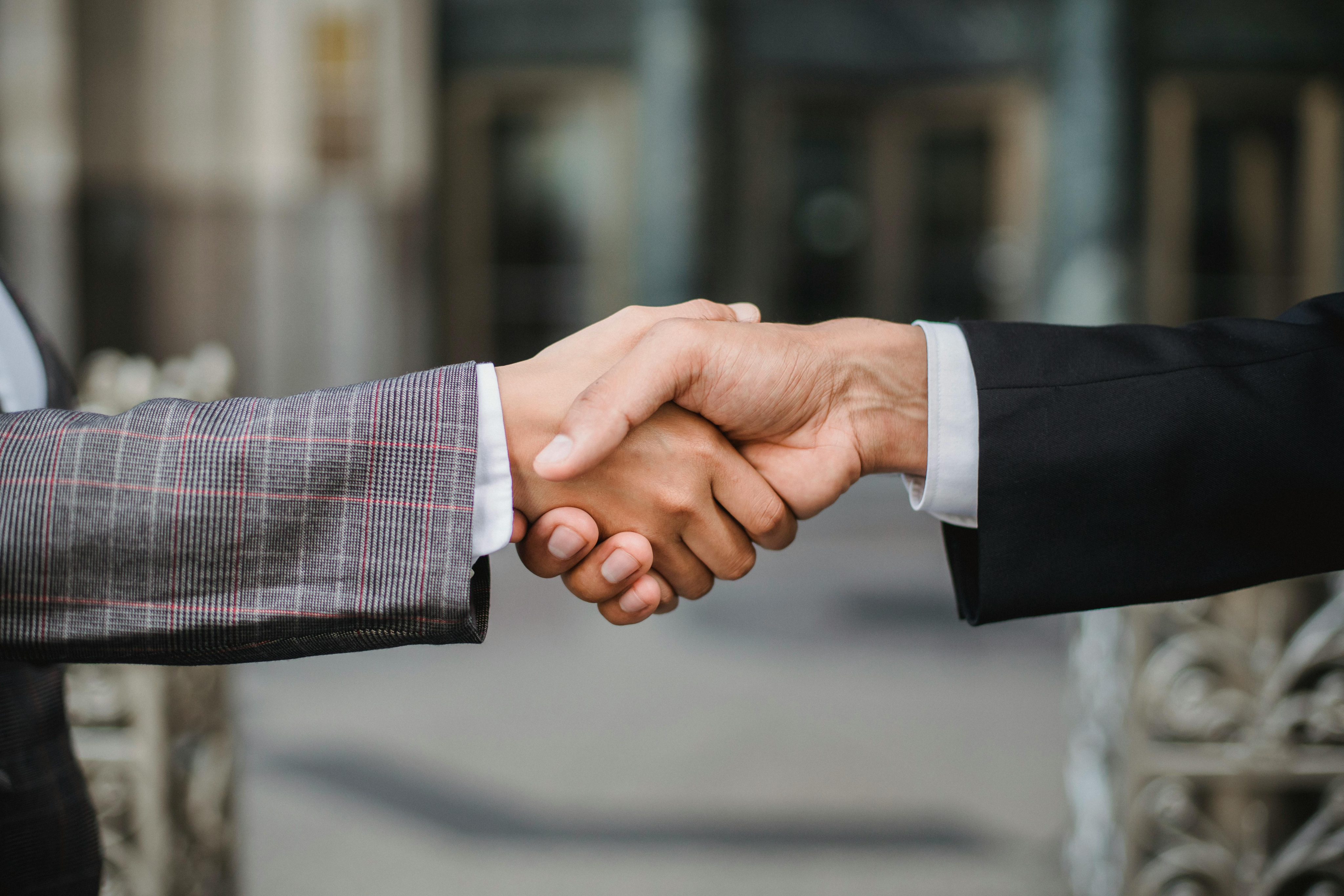Close-up of a man and woman in business attire shaking hands, symbolizing partnership, collaboration, and a shared commitment to shaping the future of technology.