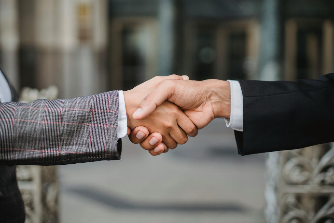 Close-up of a man and woman in business attire shaking hands, symbolizing partnership, collaboration, and a shared commitment to shaping the future of technology.