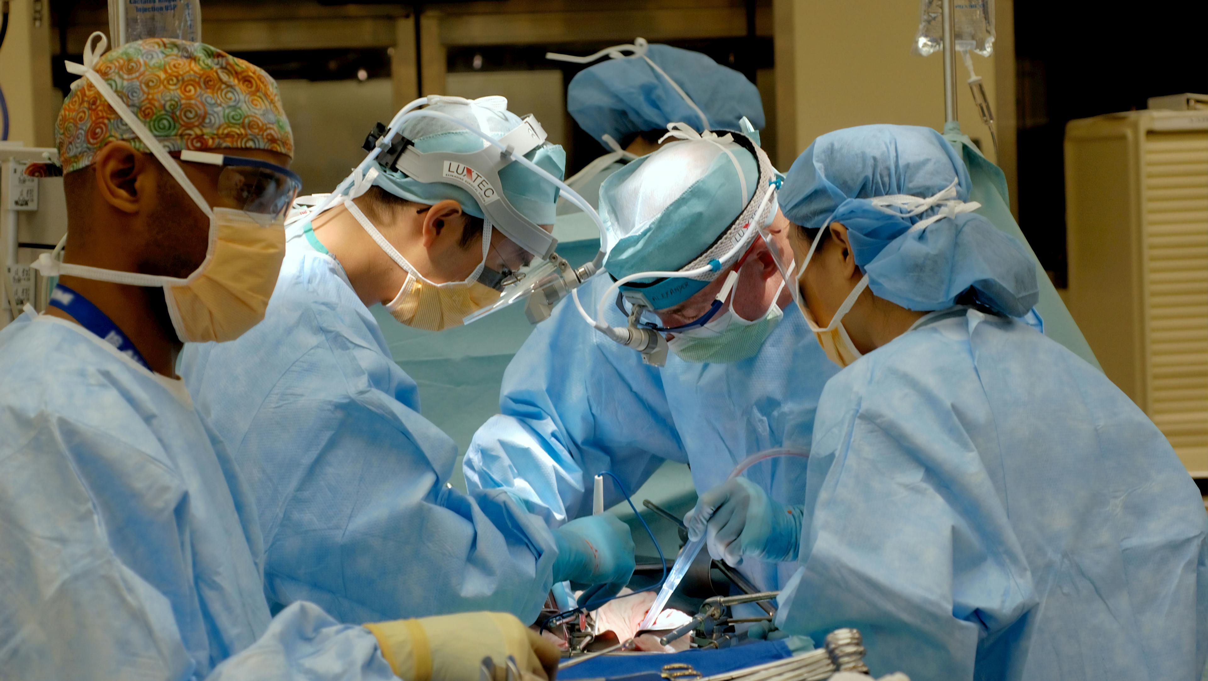 five health professionals operating on a patient in a operating room
