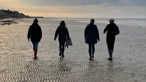 Adonis Blue team members walking along a sandy shore