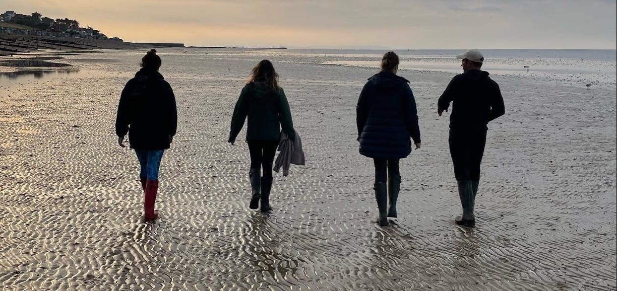 4 people walking across a beach