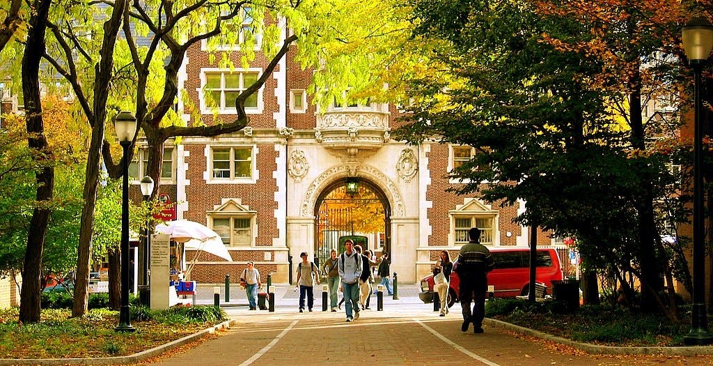 University gates with students walking toward the camera