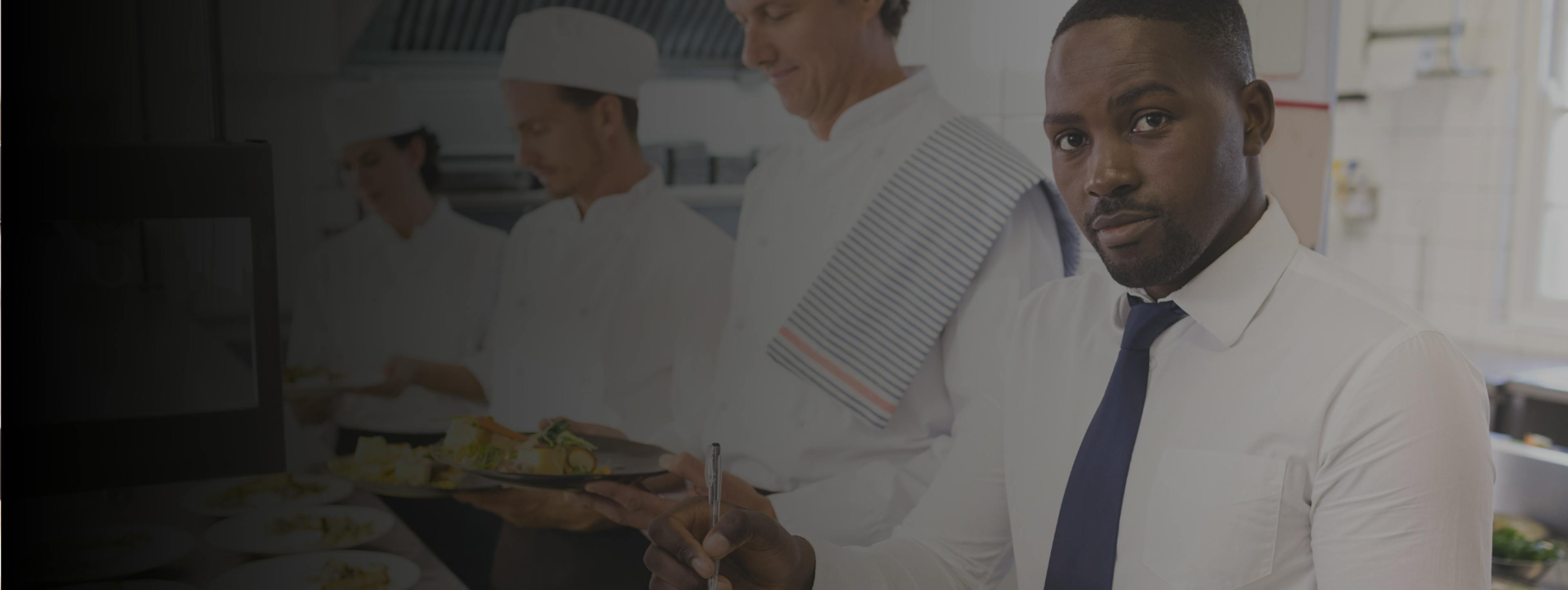 A front of house manager with three chefs standing in a commercial kitchen