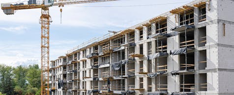 Bild eines Baukrans vor dem Rohbau eines Wohnkomplexes