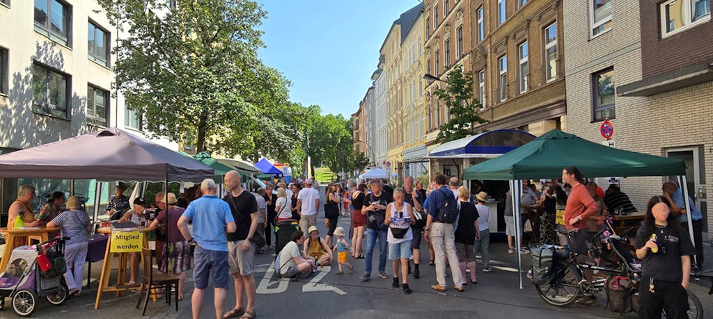 Szene vom Straßenfest des "grenzenlos e.V." mit vielen Menschen, Erwachsenen, Kindern etc., die dort stehen, sitzen und laufen.