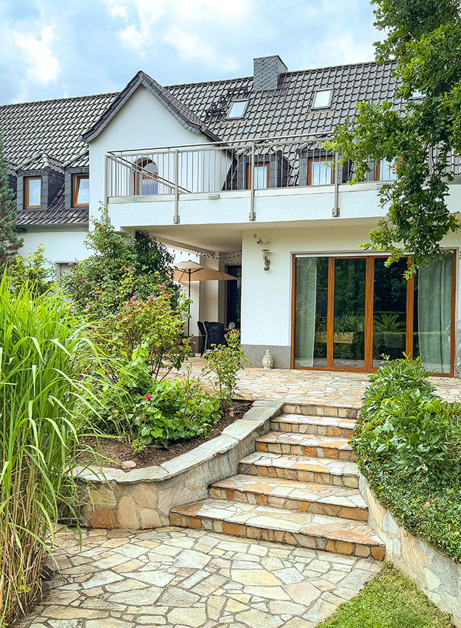 Blick aus dem Garten auf eine weiße Stadtvilla 