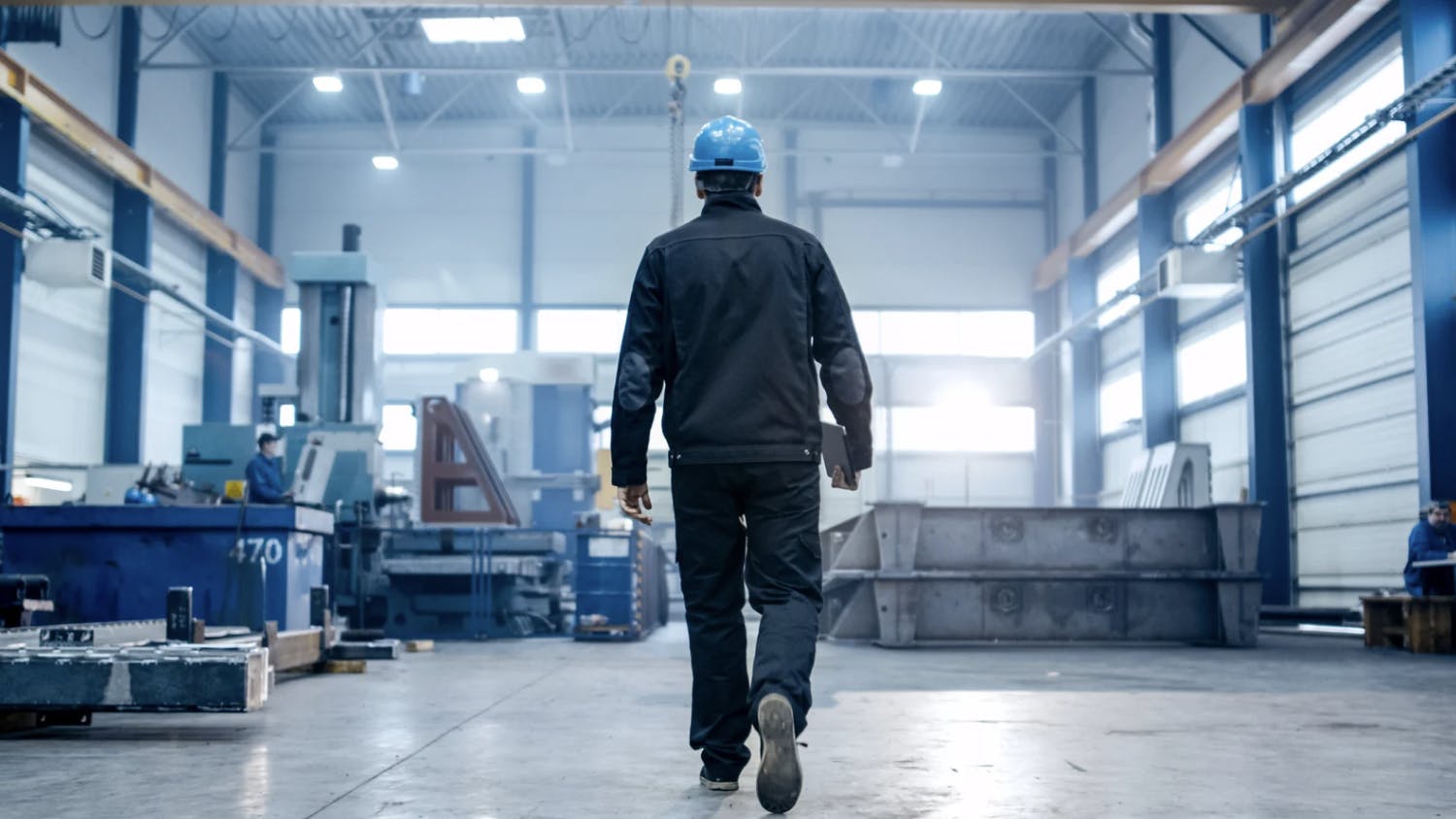 An engineer walks forward toward their job site with a tablet in hand ready to complete their task.