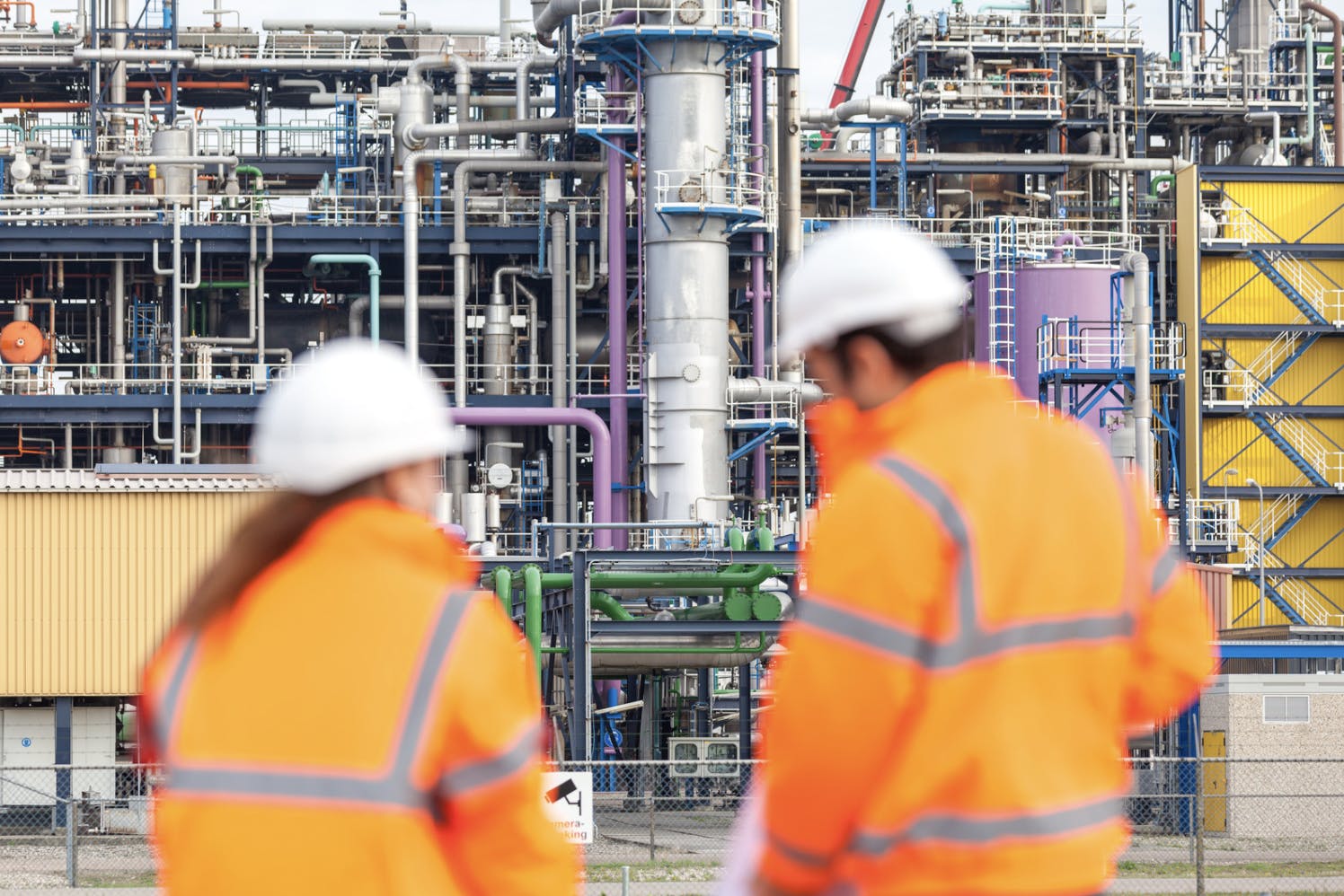 Two engineers look onto an industrial facility. Site Specific Training from Aetos Imaging is granting technicians better safety, institutional knowledge, visibility, and confidence.