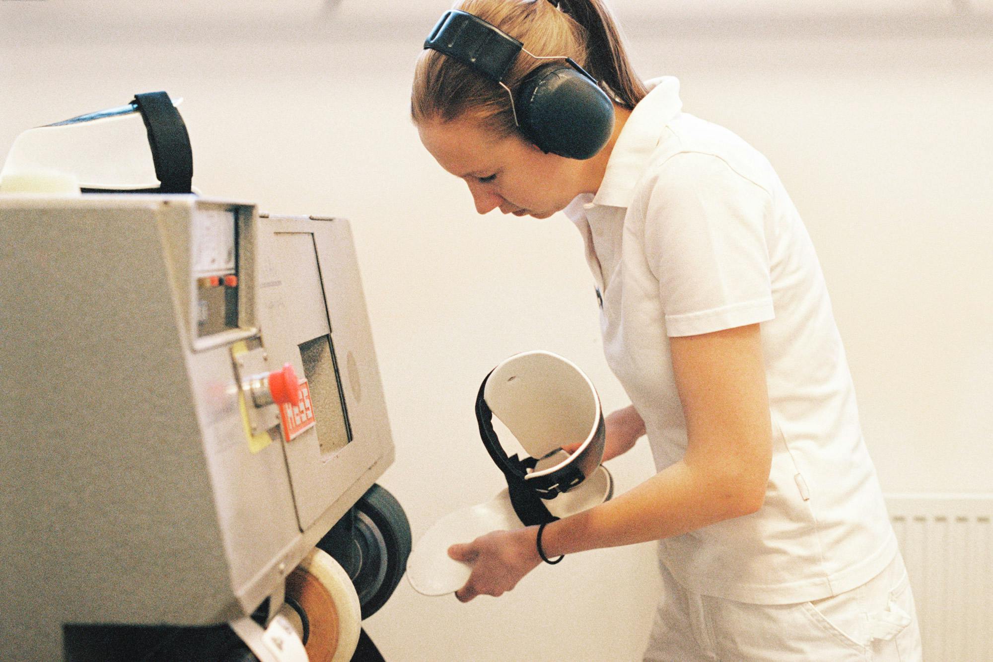 Kvinna med hörselkåpor arbetar vid en maskin. Foto: Emilia Jiménez-Bergmark, Teknikföretagen.