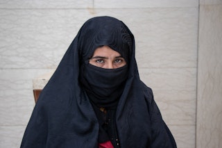 A young woman sits in a black hijab