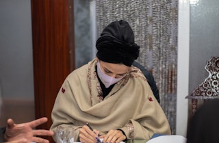 A woman takes notes at a desk.