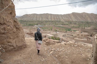 A woman in a purse stares out at mountains and a small town.