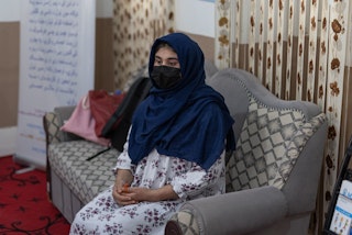 A young woman sits in a chair, looking despondent.