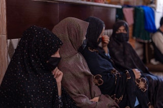 Four veiled women sitting together looking sideways.